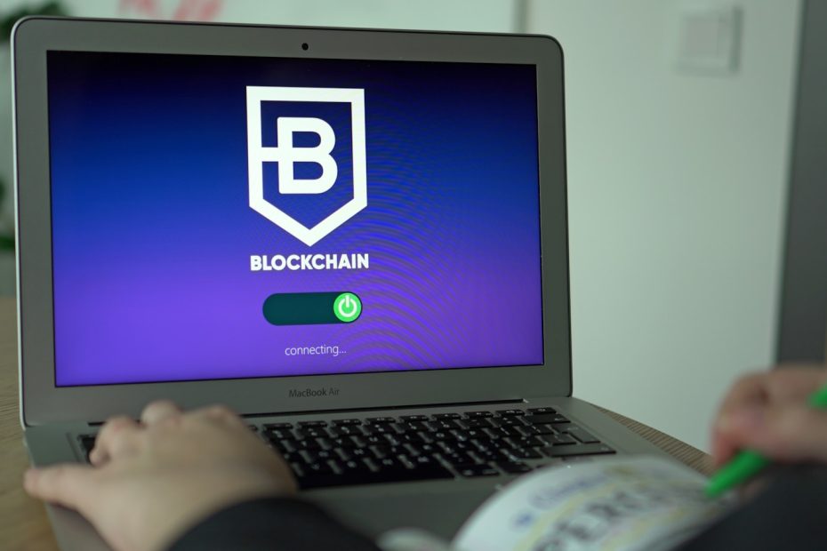 a person using a laptop with a blockchain logo on the screen